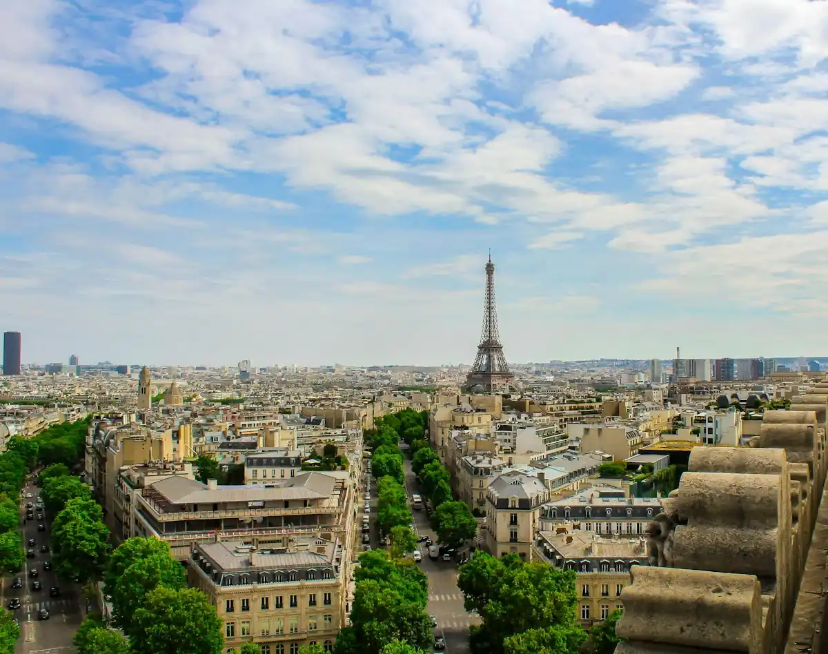 Paris rooftops under a blue sky with the Eiffel Tower in the distance.