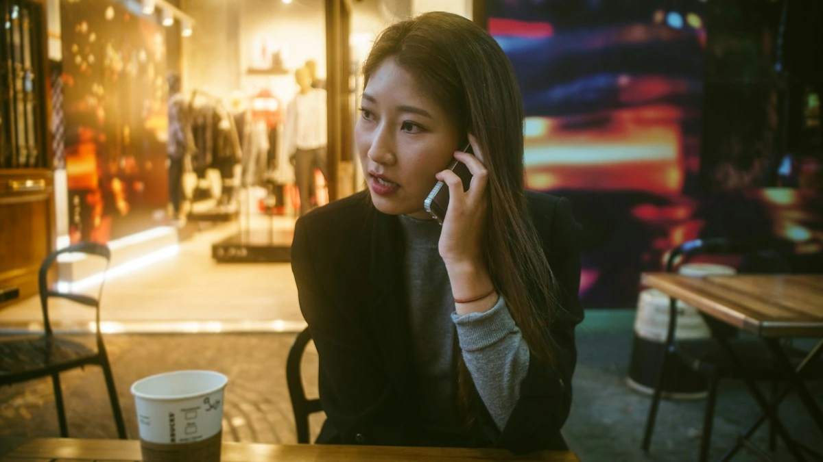 A woman talking on her phone at an outdoor cafe table in the evening.