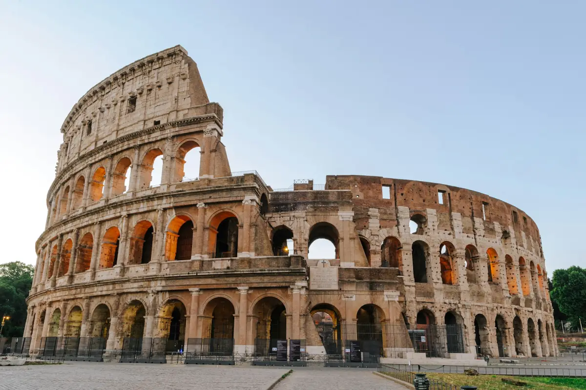 The Colosseum in Rome under a clear sky in the late afternoon.