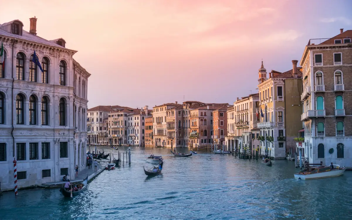 Boats on the Grand Canal in Venice, lined with old palazzi, at sunset.