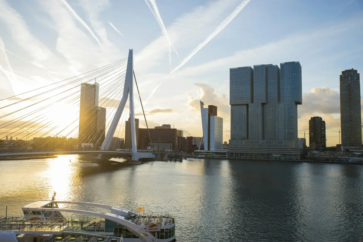The Erasmus Bridge and the Rotterdam skyline reflected in the Maas at sunrise.