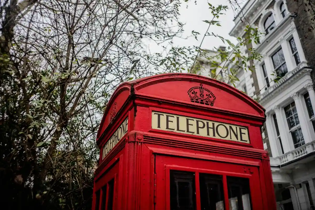A red British telephone box on a London street, representing the UK country code +44.